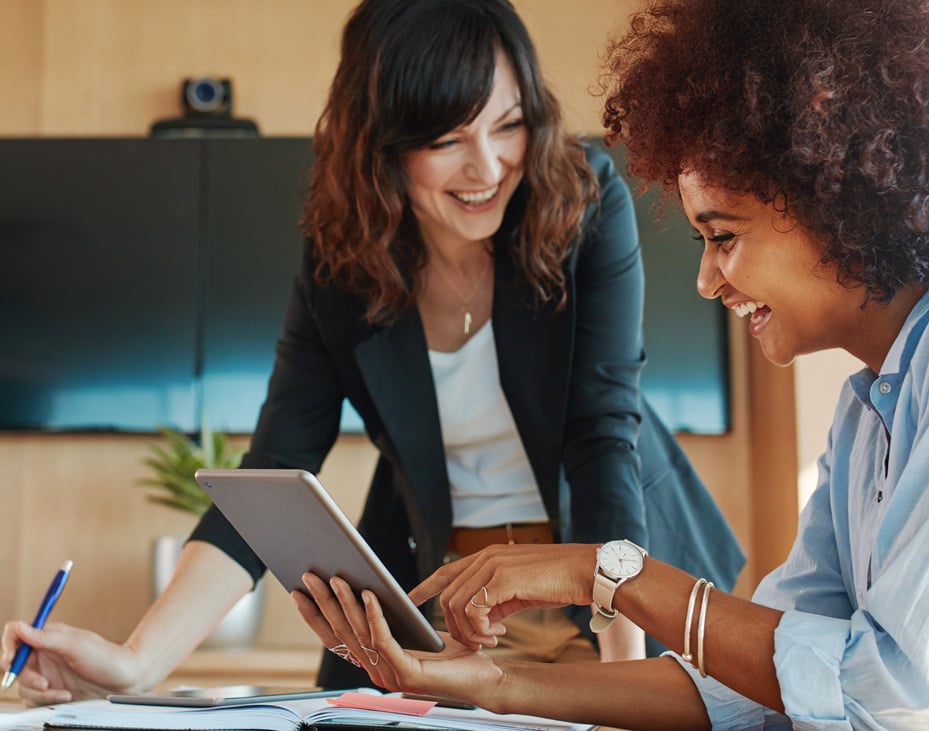 creative female executives meeting in an office using tablet and smiling